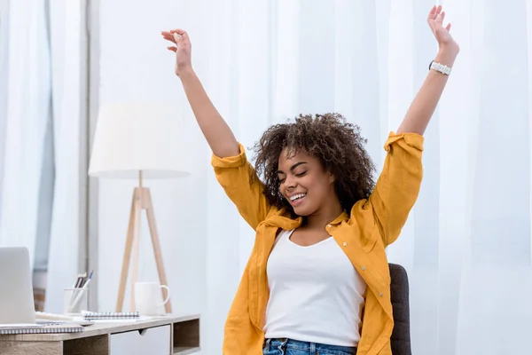 Smiling woman raising her arms in a bright, welcoming setting